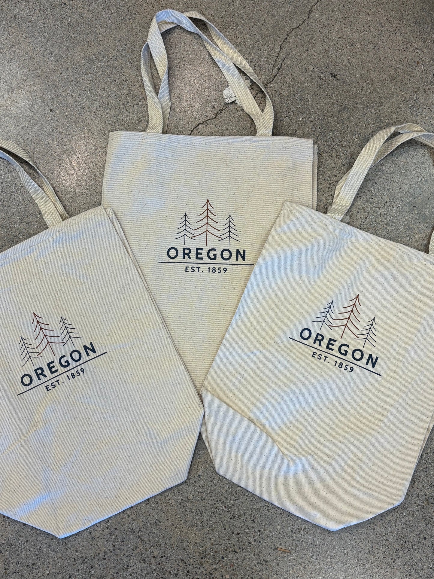"Canvas tote bag with Oregon tree line graphic and Est. 1859 text"