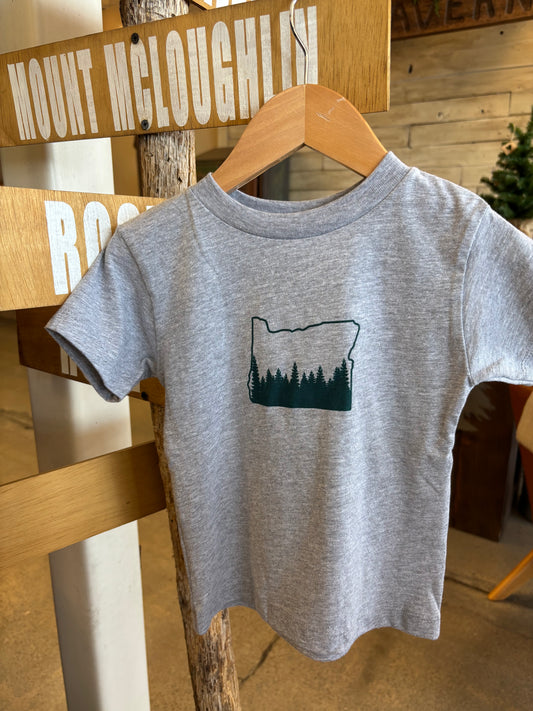 Gray t-shirt with a forest design on a wooden hanger against a wooden wall.